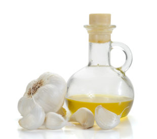 Garlic oil, isolated on a white background with fresh cloves of garlic