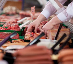 Two hands arrange meat in a display case. Image: stockfour/Shutterstock.com