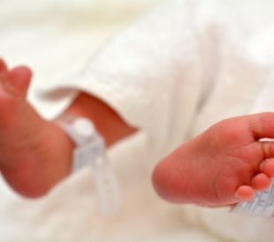 Newborn baby feet with identification tags. Image: ChameleonsEye/Shutterstock.com