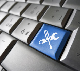 Assistance and computer service concept with toolkit icons and symbol on a blue laptop computer key for website and online business. Image: niroworld/Shutterstock.com.