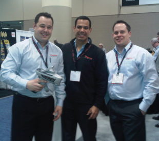 Happy booth staff posing with handheld XRF analyzer at PDAC
